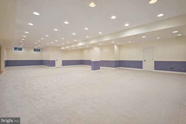 basement with a wainscoted wall, recessed lighting, visible vents, and light colored carpet