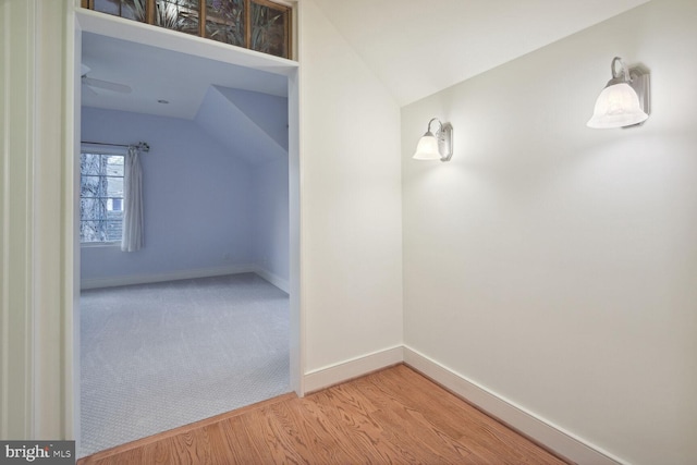 additional living space with baseboards, vaulted ceiling, wood finished floors, and carpet flooring