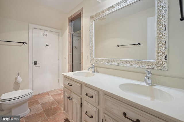 bathroom with toilet, double vanity, stone finish floor, and a sink