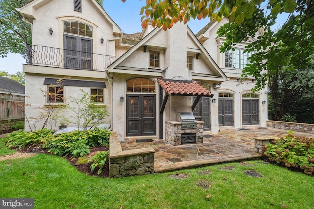 back of property featuring a balcony, stucco siding, a patio area, and french doors