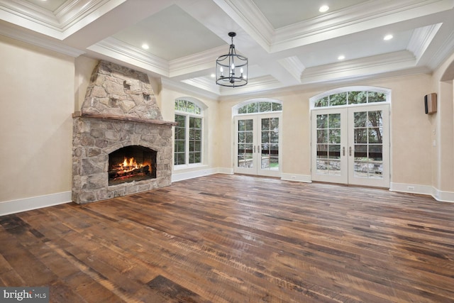 unfurnished living room featuring french doors, a healthy amount of sunlight, wood-type flooring, and a stone fireplace