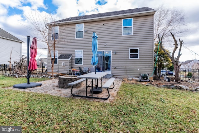 rear view of property featuring a yard, a patio area, and an outdoor fire pit