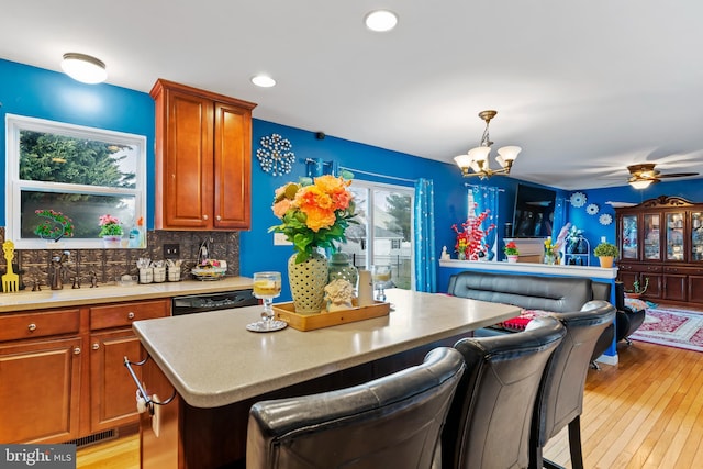 kitchen featuring a breakfast bar, sink, hanging light fixtures, dishwasher, and a kitchen island