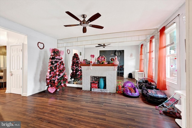 misc room with ceiling fan, dark hardwood / wood-style flooring, and a brick fireplace