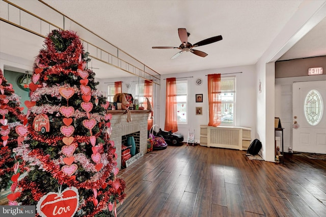 unfurnished living room featuring radiator, dark hardwood / wood-style floors, a brick fireplace, and ceiling fan