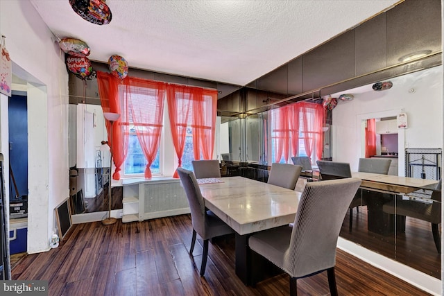 dining area featuring dark wood-type flooring and a textured ceiling