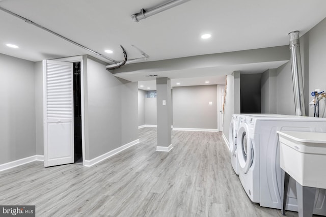 laundry area with sink, washing machine and dryer, and light hardwood / wood-style floors