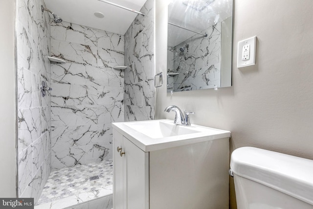 bathroom featuring tiled shower, vanity, and toilet