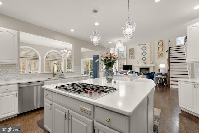 kitchen with appliances with stainless steel finishes, a fireplace, a sink, and tasteful backsplash