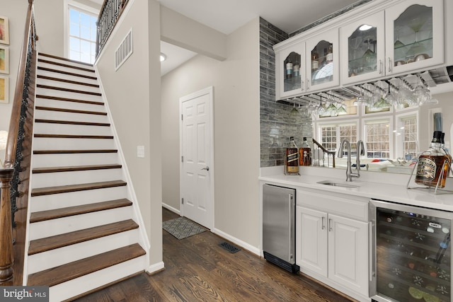 bar featuring beverage cooler, a sink, stairs, high end fridge, and indoor wet bar