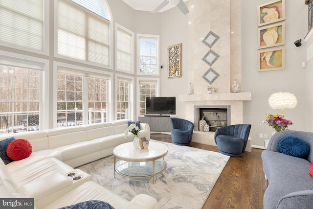 living area with a towering ceiling, a premium fireplace, baseboards, and dark wood-type flooring