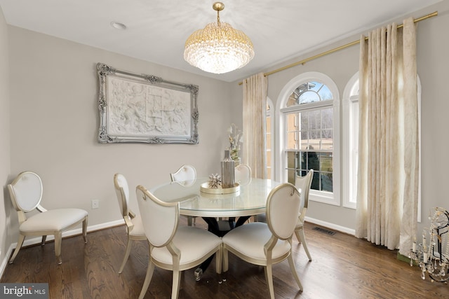 dining area featuring a chandelier, wood finished floors, visible vents, and baseboards