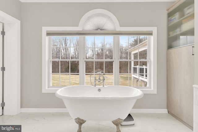 full bath featuring marble finish floor, a freestanding tub, and baseboards