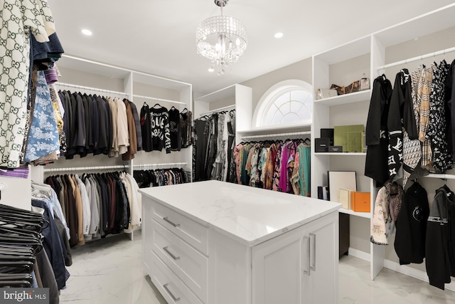 spacious closet featuring an inviting chandelier and marble finish floor