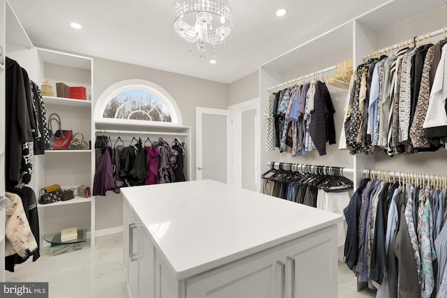 walk in closet with marble finish floor and a notable chandelier