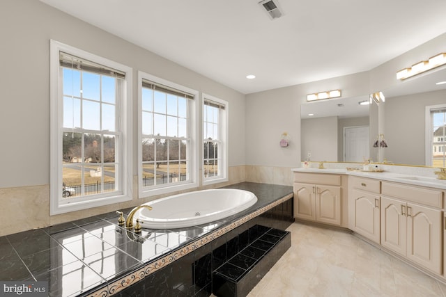 full bath featuring double vanity, a garden tub, visible vents, and a sink