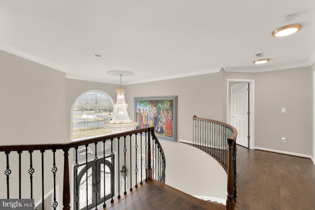 corridor featuring a notable chandelier, dark wood-type flooring, an upstairs landing, baseboards, and crown molding