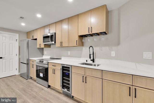 kitchen featuring beverage cooler, visible vents, stainless steel appliances, light brown cabinetry, and a sink