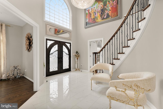 foyer entrance featuring baseboards, stairway, marble finish floor, french doors, and a notable chandelier