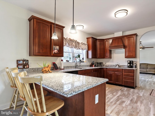 kitchen with a breakfast bar, kitchen peninsula, sink, and hanging light fixtures