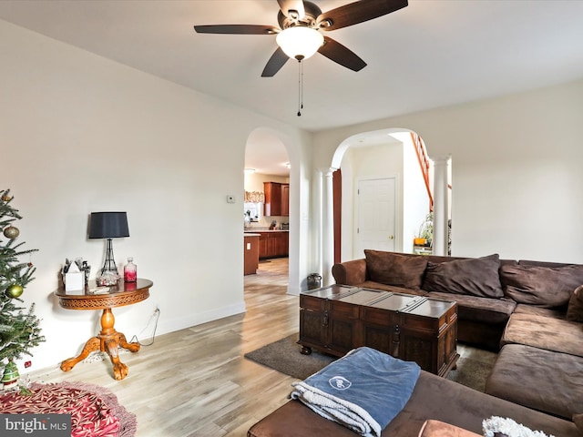 living room with light hardwood / wood-style flooring, ceiling fan, and ornate columns