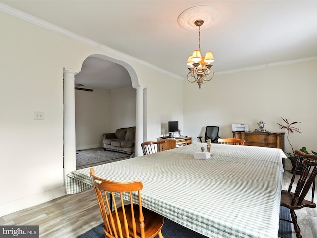 dining space with decorative columns, crown molding, a chandelier, and light hardwood / wood-style floors