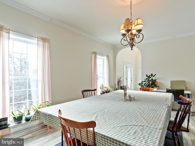 dining space with an inviting chandelier, crown molding, and wood-type flooring