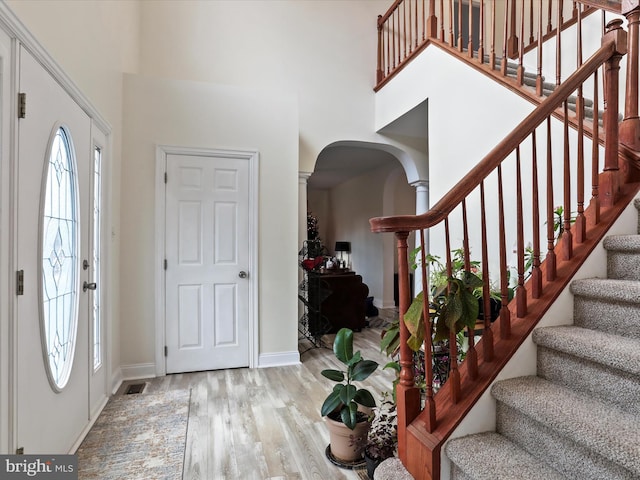 foyer featuring wood-type flooring, a high ceiling, and ornate columns