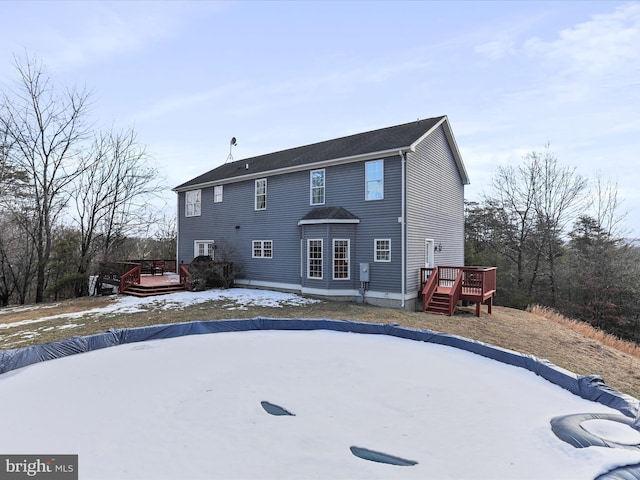 snow covered house featuring a wooden deck