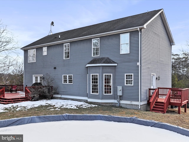 snow covered back of property featuring a deck