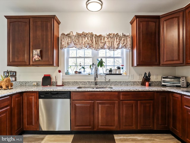 kitchen featuring light stone counters, dishwasher, and sink