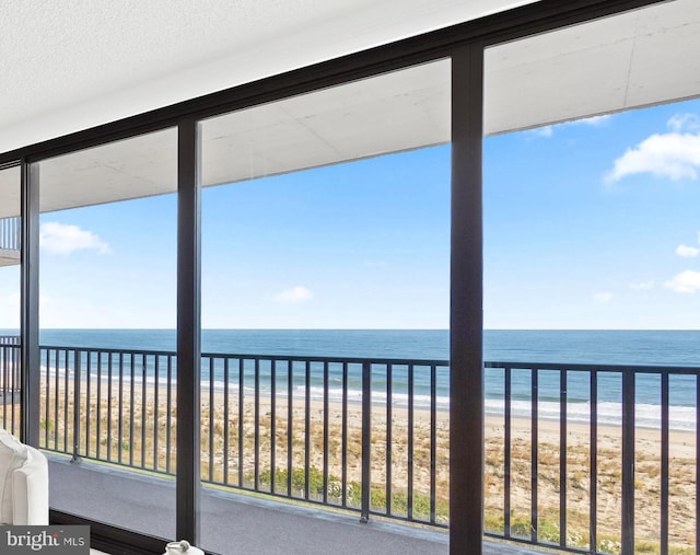 unfurnished sunroom featuring a water view and a beach view