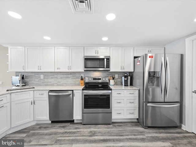 kitchen featuring dark wood-type flooring, sink, white cabinetry, tasteful backsplash, and appliances with stainless steel finishes