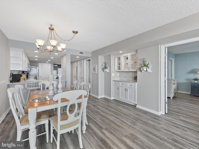 dining room featuring an inviting chandelier, hardwood / wood-style floors, sink, and a textured ceiling