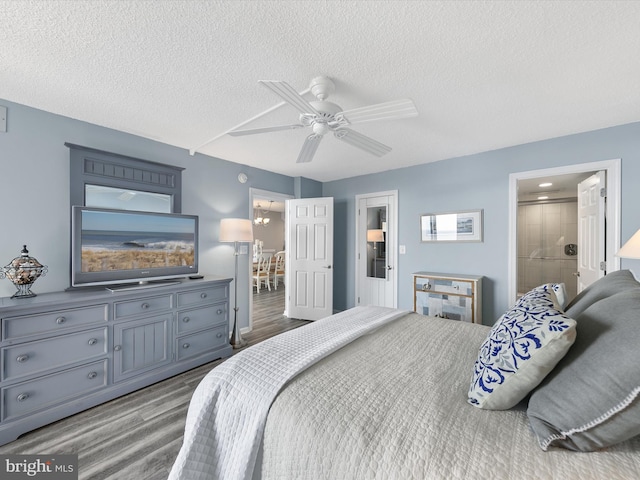 bedroom with ceiling fan, hardwood / wood-style floors, ensuite bathroom, and a textured ceiling