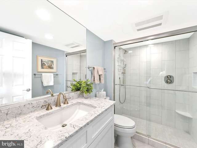 bathroom featuring vanity, a shower with door, and toilet