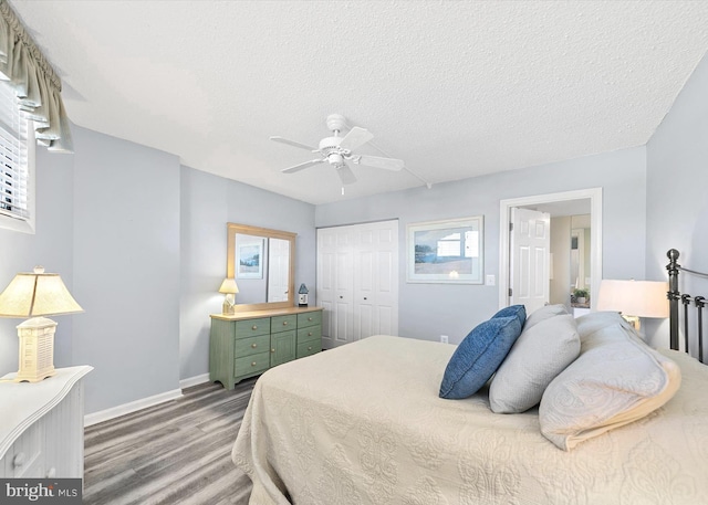 bedroom featuring multiple windows, wood-type flooring, ceiling fan, a textured ceiling, and a closet