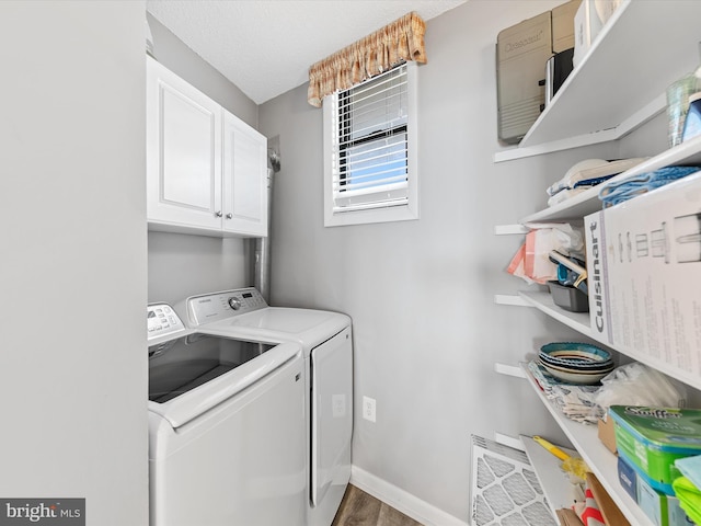 laundry room with cabinets, washer and dryer, dark wood-type flooring, and a textured ceiling