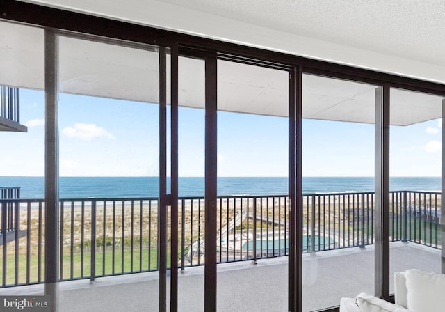 unfurnished sunroom with a water view and a view of the beach