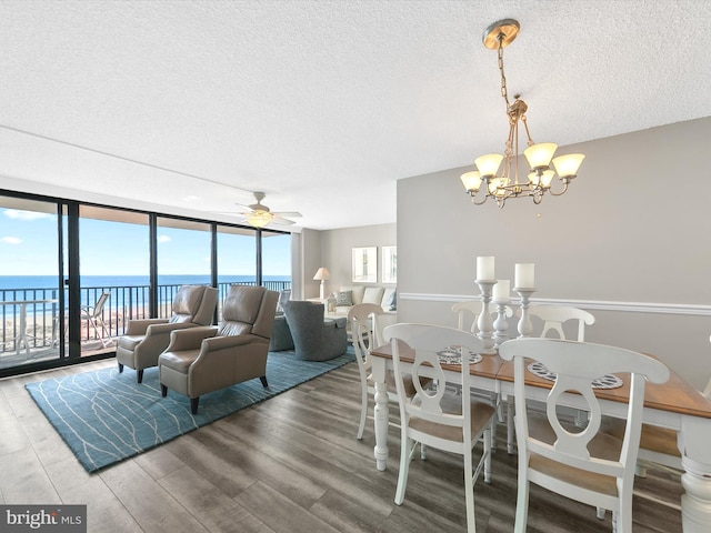 dining area with a water view, expansive windows, hardwood / wood-style floors, and a textured ceiling