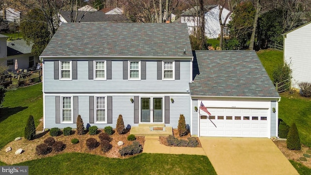 colonial home with a front yard, a tiled roof, a garage, and driveway