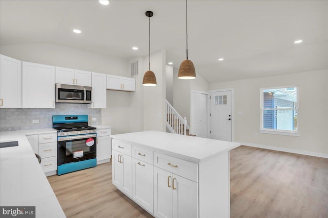 kitchen featuring lofted ceiling, light wood finished floors, stainless steel appliances, decorative backsplash, and white cabinetry