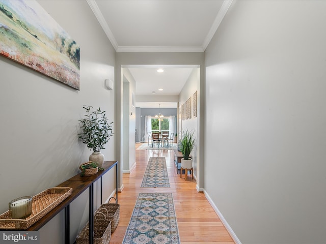 hall with an inviting chandelier, crown molding, and light wood-type flooring