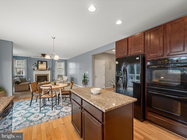 kitchen featuring light stone counters, light hardwood / wood-style floors, a kitchen island, and black appliances