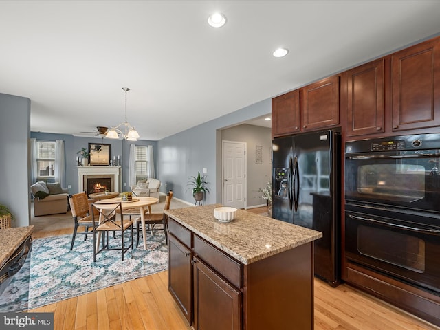 kitchen featuring a kitchen island, light hardwood / wood-style flooring, light stone counters, and black appliances