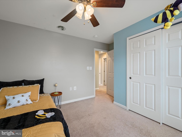 bedroom with light colored carpet, ceiling fan, and a closet