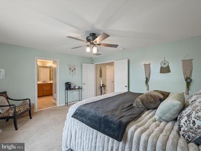 bedroom featuring ceiling fan, ensuite bath, sink, and light carpet