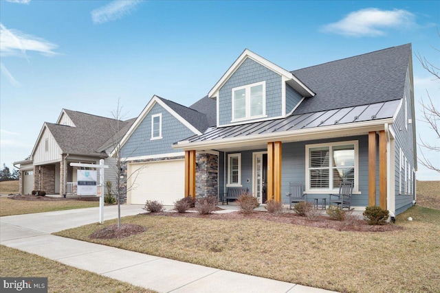 view of front of house with a garage, a front yard, and covered porch