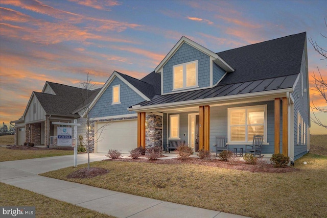 view of front facade featuring driveway, a porch, a standing seam roof, and a front lawn