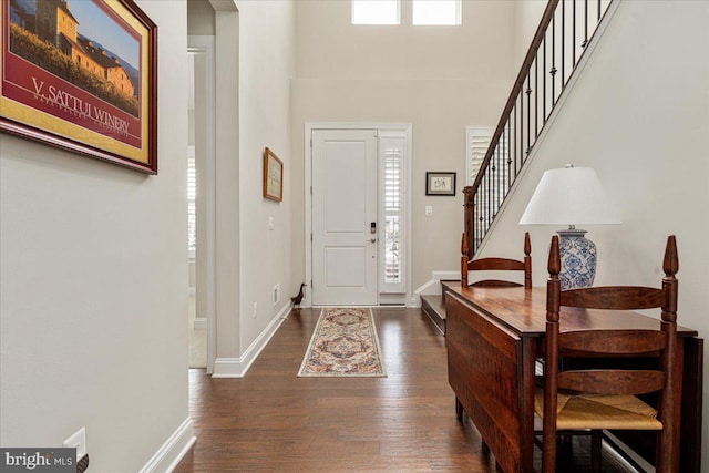 foyer with baseboards, dark wood finished floors, a high ceiling, and stairs